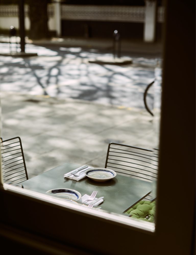 Outside table dappled in sunshine shot through the window and Vori London Greek Restaurant